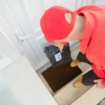 Kurir berseragam merah mengantarkan paket ke depan pintu rumah, menggambarkan layanan COD atau bayar di tempat